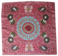 Decorative pink fabric with a central blue floral design and surrounding patterns